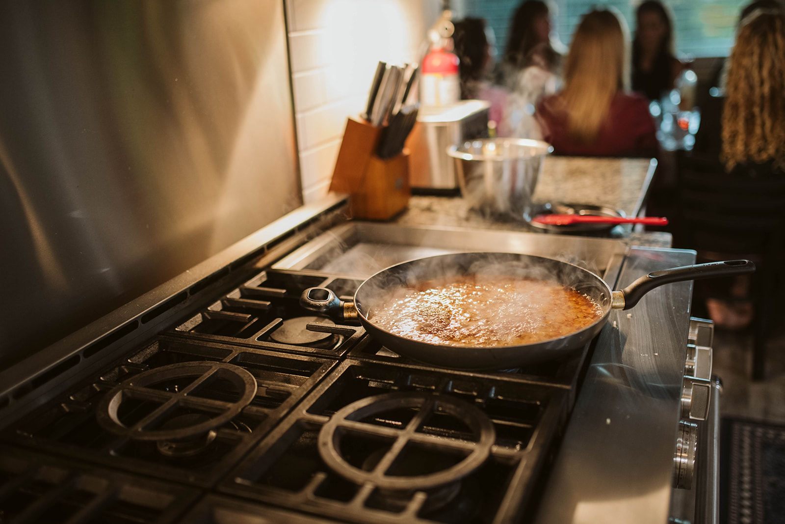 Chef-prepared meal simmering on the stove while the group gathers behind