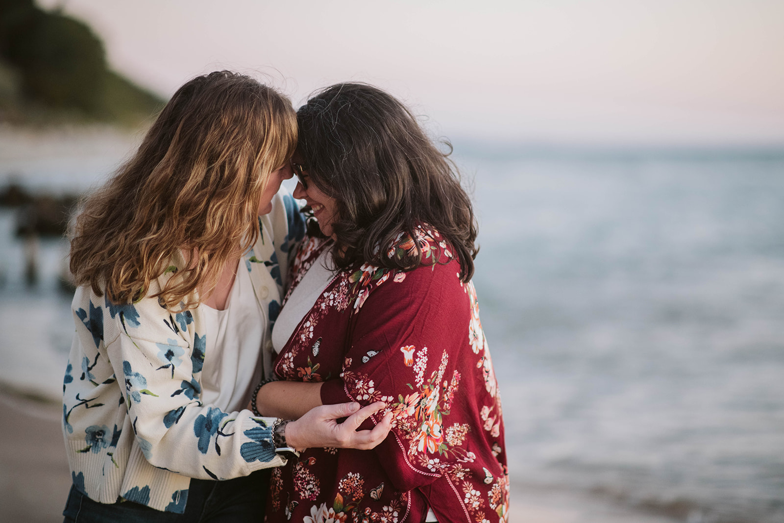 Two retreat participants leaning foreheads together on the beach at sunset